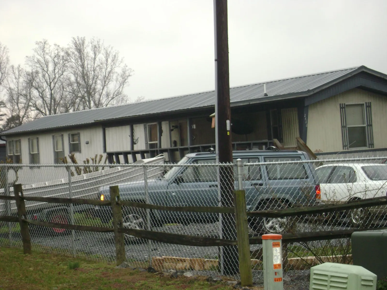 Dark metal roof on a long single story building behind a chain link fence in Bradford